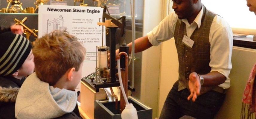 Objects of Invention: student engineer giving a demonstration of a model Newcomen steam pump